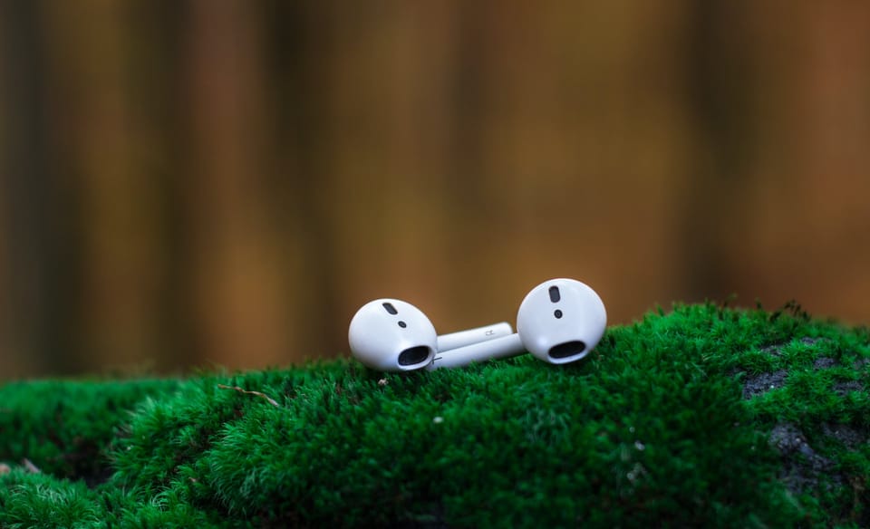 shallow focus photography of white airpods on green surface